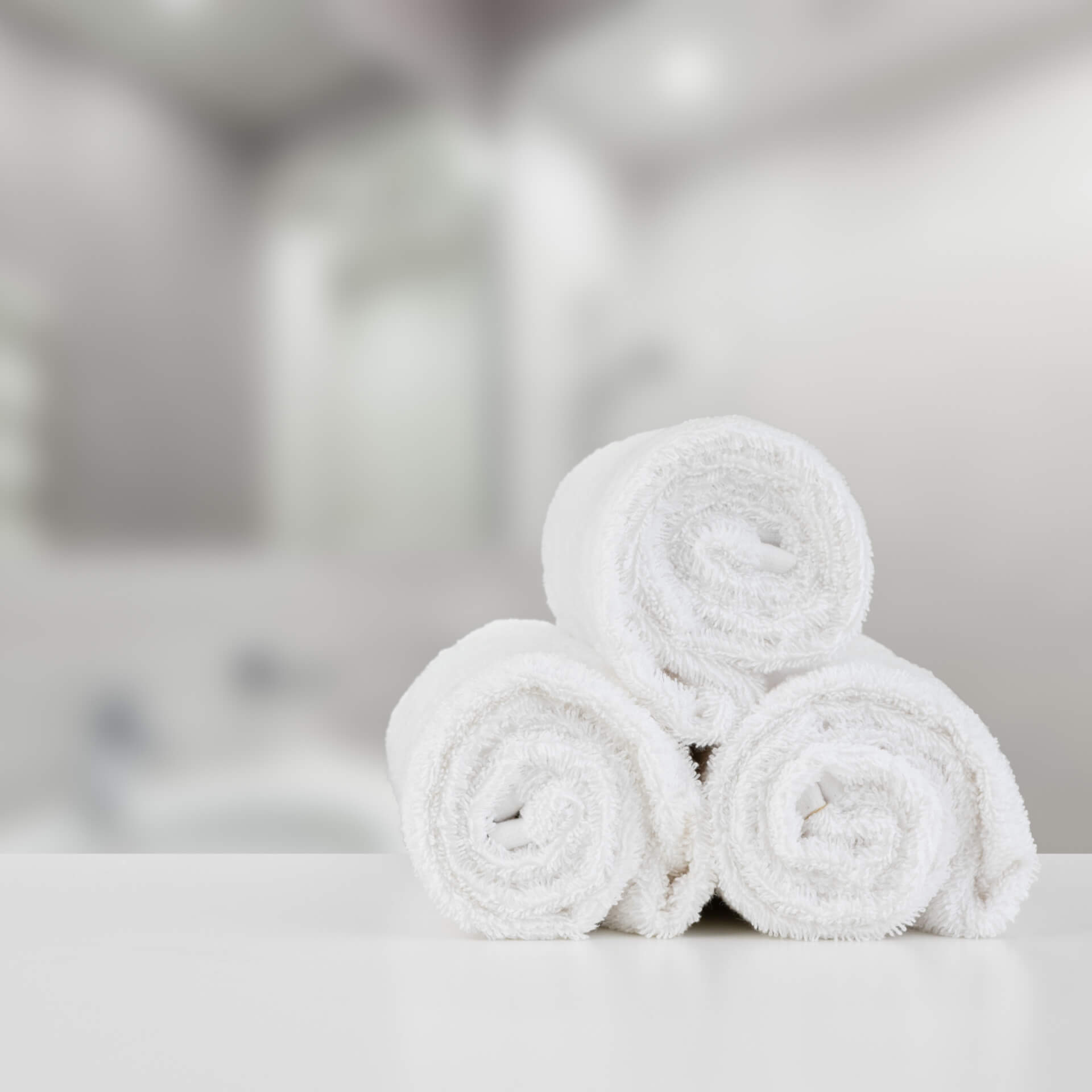 rolled-stacked-white-spa-towels-table-against-blurred-backgroundedit